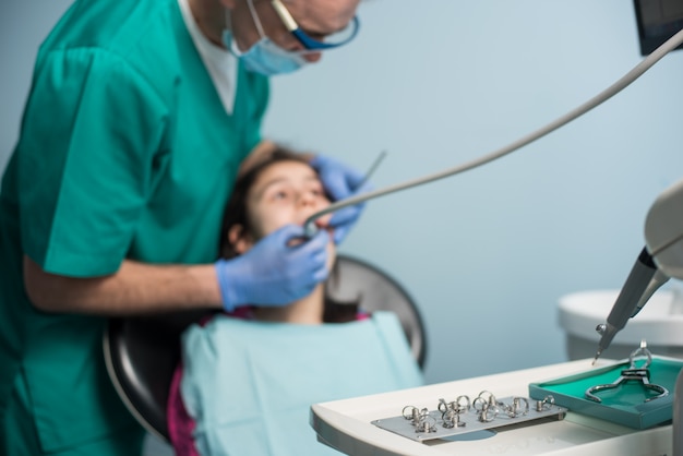 Jeune fille lors de la première visite dentaire. Dentiste pédiatrique senior traitant les dents des patientes au cabinet dentaire