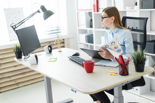 Photo une jeune fille à lunettes est assis à une table dans le bureau