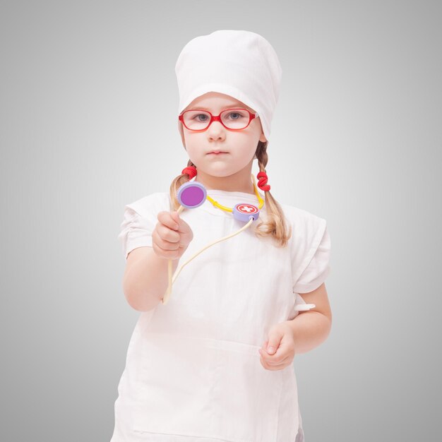 Jeune fille à lunettes joue chez le médecin en tant que maman