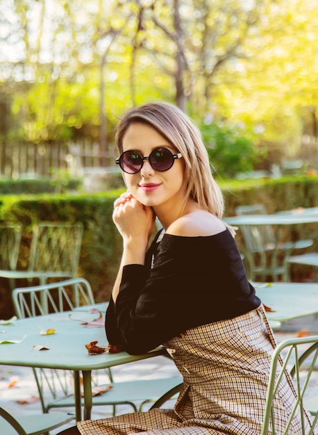 Jeune fille à lunettes de soleil assis chaise au café