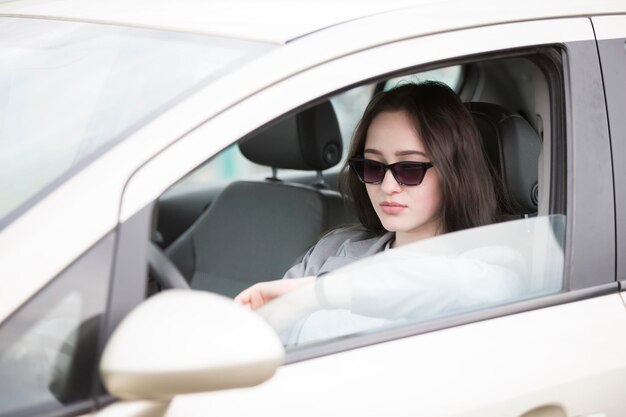 Jeune fille à lunettes de soleil dans la voiture