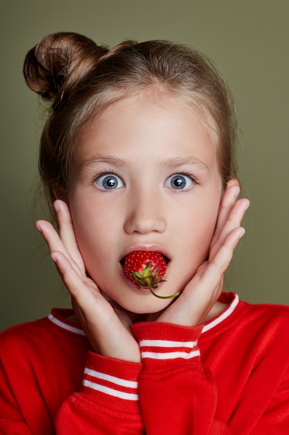 Jeune fille mange des émotions gaies à la fraise