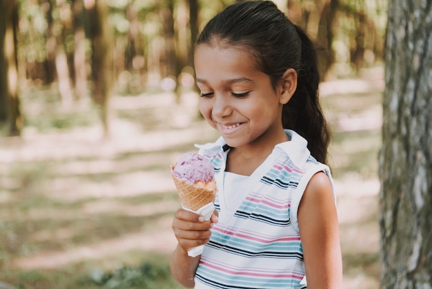 Jeune fille mange une glace en bois.