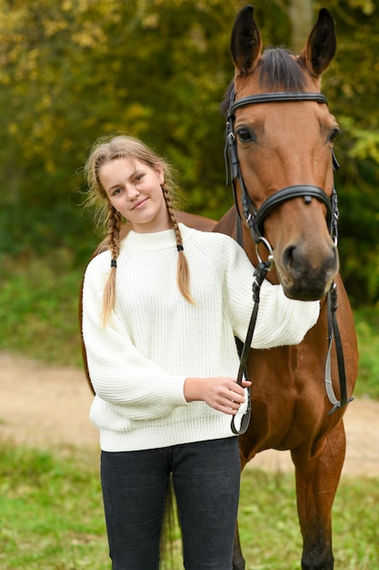 Jeune fille marchant avec un cheval dans la nature.