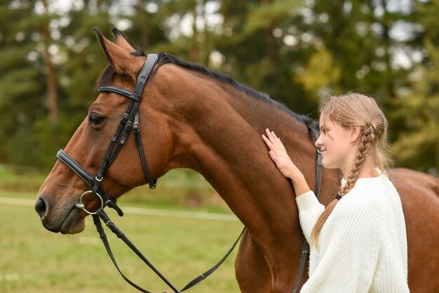 Jeune fille marchant avec un cheval dans la nature.