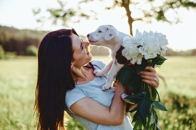 La jeune fille marche avec un chiot dans un champ de vélo à l’arrière de la lumière du soleil