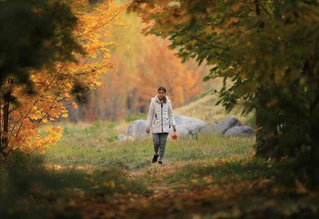 une jeune fille marche dans l'allée des érables d'automne