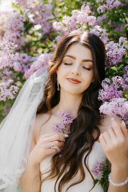 Jeune fille mariée en robe blanche dans une forêt de printemps dans des buissons de lilas