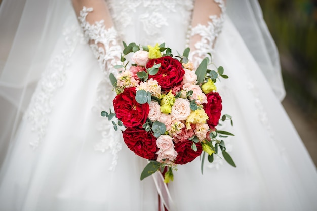 Jeune fille mariée en séjour dans la rue de la ville et attend le marié avec bouquet de roses rouges et blanches