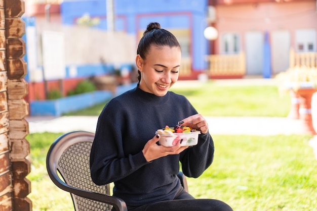Jeune fille marocaine tenant un bol de fruits à l'extérieur