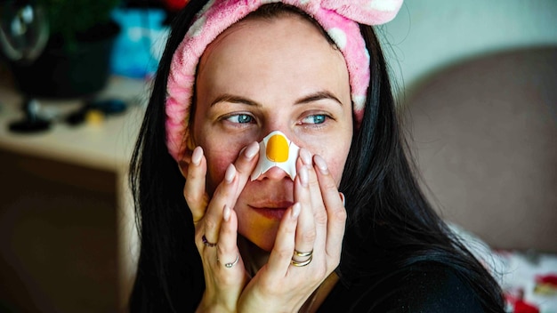 Jeune fille avec un masque facial regardant la caméra sur fond intérieur Procédure cosmétique Spa de beauté