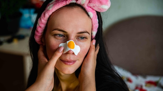 Jeune fille avec un masque facial regardant la caméra sur fond intérieur Procédure cosmétique Spa de beauté