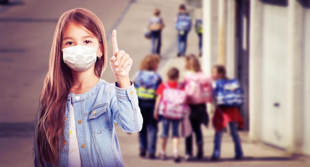 Jeune fille avec masque de protection contre le virus corona à l'école.