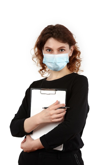 Jeune fille avec un masque de protection sur le visage avec un cahier et un stylo dans les mains.