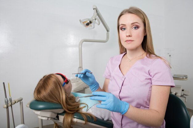 Jeune fille médecin dentaire tenant un instrument médical dans le contexte d'un cabinet dentaire