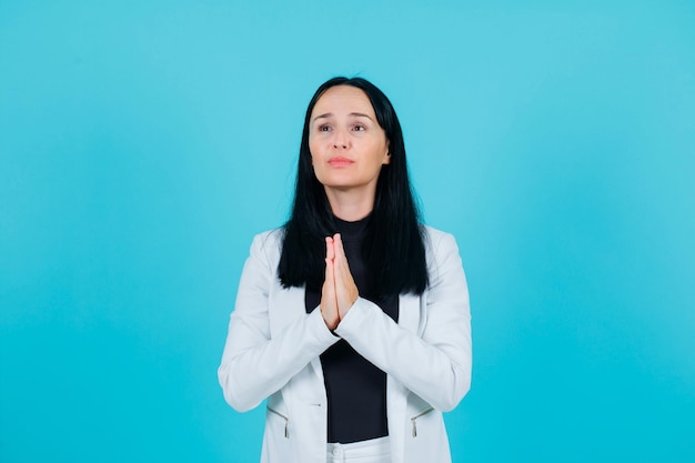 Jeune fille mendie en se tenant la main sur fond bleu