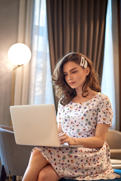 Jeune fille mignonne en robe travaillant sur un ordinateur portable dans un café