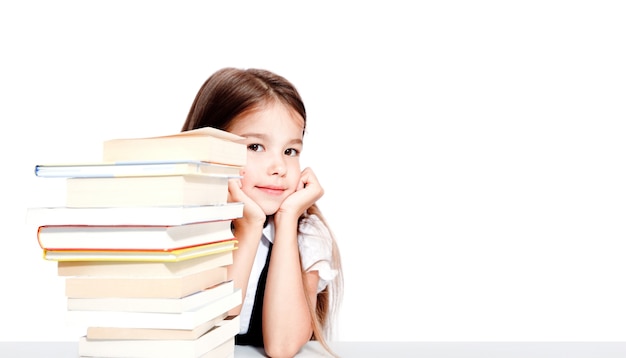 Jeune fille mignonne s'asseyant à la table et lisant un livre