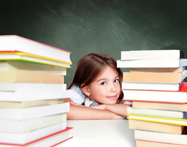 Jeune fille mignonne s'asseyant à la table et lisant un livre