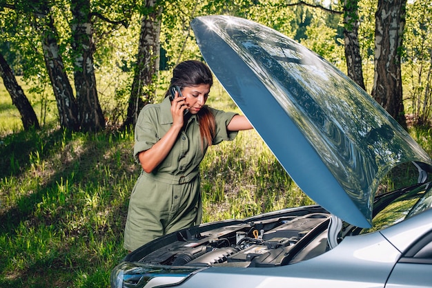 Une jeune fille mince appelle le centre des machines et explique la cause de la panne de sa voiture afin qu'ils puissent l'aider à comprendre quoi faire