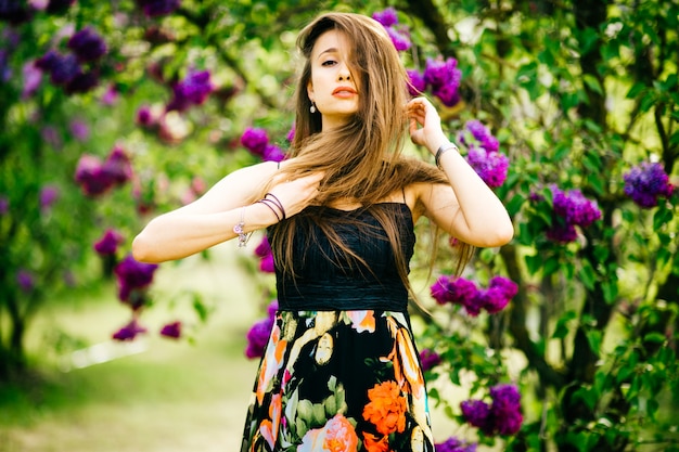 Jeune Fille à La Mode Brunnette Posant Pour La Caméra Dans Le Parc Fleuri De Printemps.