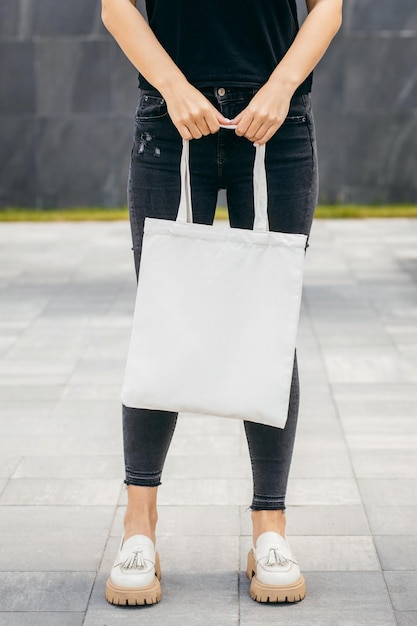 Jeune fille modèle asiatique dans la rue tenant une maquette de sac écologique blanc