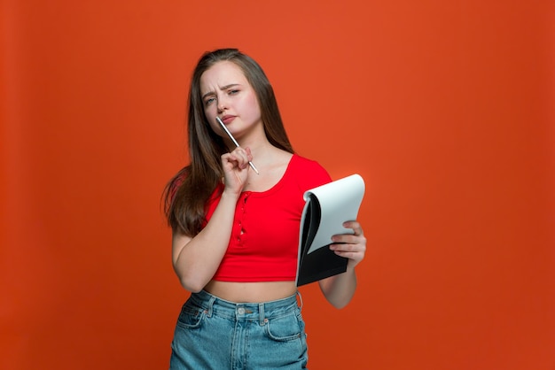 Jeune fille moderne et créative avec un bloc-notes et un crayon réfléchissez à des idées de projets pour faire la liste des choses à faire sur