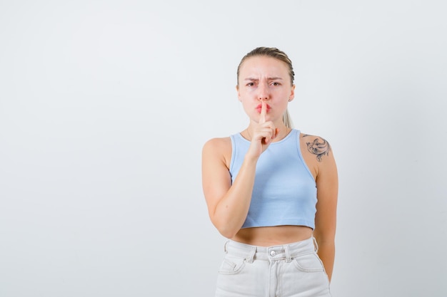 jeune fille montre un geste de silence sur fond blanc