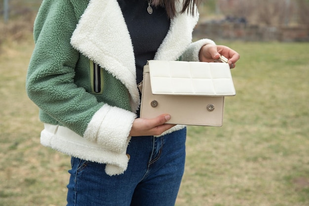 Une jeune fille montre un sac à main à l'extérieur