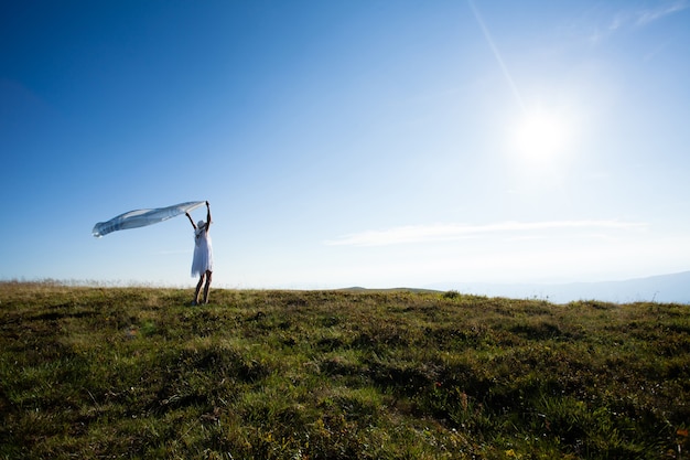 Photo jeune fille avec un mouchoir en papier, profitant de la lumière du soleil au sommet de la montagne