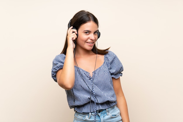 Jeune fille sur mur isolé, écouter de la musique avec des écouteurs