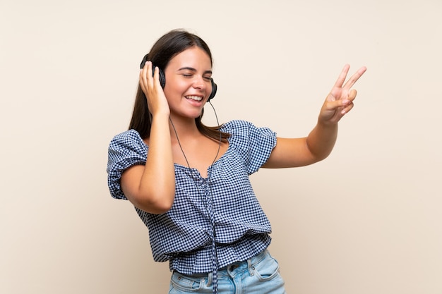 Jeune fille sur mur isolé, écouter de la musique avec des écouteurs