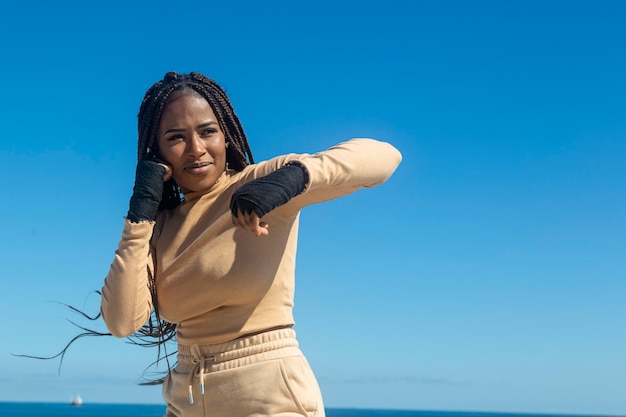 Jeune fille noire afro formation arts martiaux, boxe en plein air avec mer et ciel bleu