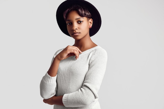 Jeune fille noire belle hipster en pull et bonnet blanc