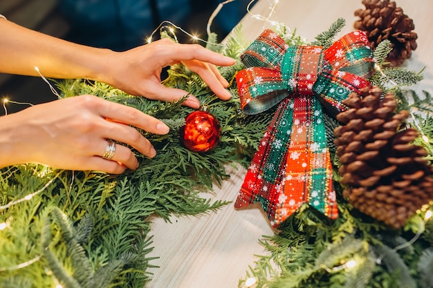 Jeune fille orne une guirlande de Noël de brindilles de sapin et de pin, une guirlande,