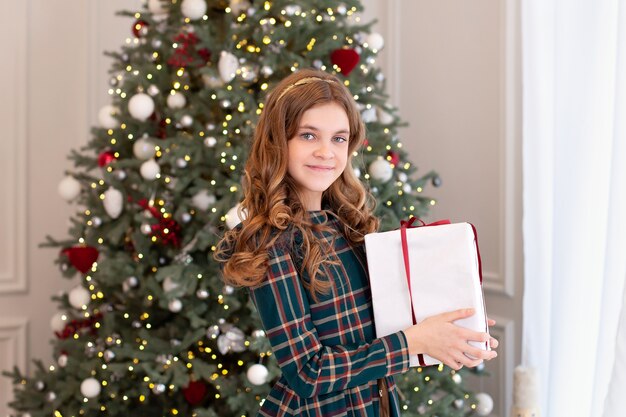 Jeune fille ouvre le cadeau de Noël dans le salon