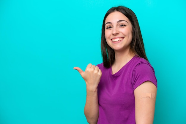 Jeune fille avec des pansements isolés sur fond bleu pointant vers le côté pour présenter un produit