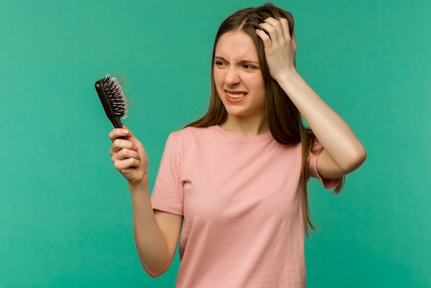 Jeune fille avec un peigne et des problèmes de cheveux sur bleu