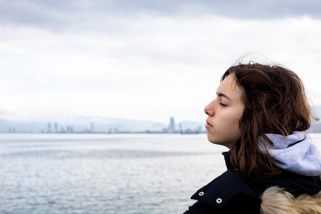 Jeune fille pensive regardant vers la mer depuis le bateau