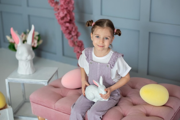 Jeune fille avec des petits pains de coiffure tenant un lapin jouet dans ses mains