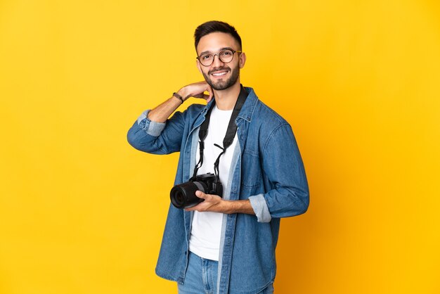 Jeune fille photographe isolée sur mur jaune en riant