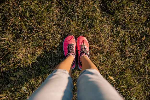 Jeune fille pieds jambes en baskets sur le pré vert