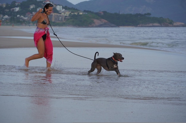 Jeune fille et pit-bull dog dans un moment d'affection sur la plage de Piratininga, Rio de Janeiro