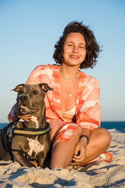 Jeune fille et pit-bull dog dans un moment d'affection sur la plage de Saquarema à Rio de Janeiro. Coucher de soleil.