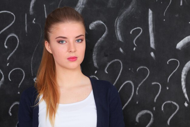 Jeune fille avec point d'interrogation sur fond gris.