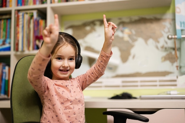 Une jeune fille portant des écouteurs profite de son éducation à distance Étudiant à distance l'école à la maison