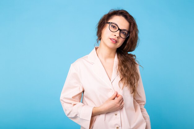 Jeune fille posant en pyjama sur mur bleu