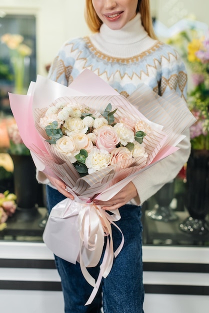 Une jeune fille pose avec un beau bouquet festif dans le contexte d'un magasin de fleurs confortable Fleuristerie et confection de bouquets dans un magasin de fleurs Petite entreprise