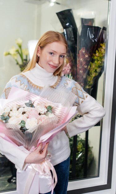 Une jeune fille pose avec un beau bouquet festif dans le contexte d'un magasin de fleurs confortable Fleuristerie et confection de bouquets dans un magasin de fleurs Petite entreprise