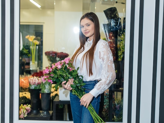 Une jeune fille pose avec un beau bouquet festif dans le contexte d'un magasin de fleurs confortable Fleuristerie et confection de bouquets dans un magasin de fleurs Petite entreprise